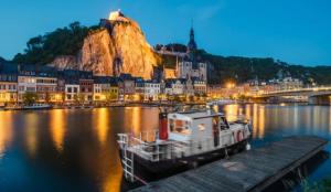 a boat is docked at a dock in a river at La MeusÂme in Dinant
