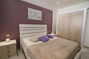 una camera da letto con un grande letto con cuscini viola di Casa Giuditta Deluxe a Otranto a Otranto