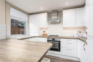 Cairn Suite - Donnini Apartments في آير: مطبخ بدولاب بيضاء وطاولة خشبية