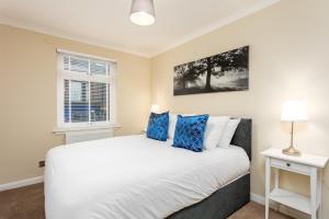 Cairn Suite - Donnini Apartments في آير: غرفة نوم مع سرير أبيض كبير مع وسائد زرقاء