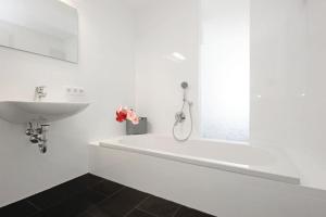 a white bathroom with a sink and a bath tub at Appartement Falkenstein in Nesselwang
