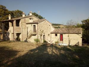 una vieja casa de piedra con una puerta roja en Casa in campagna per vacanze in Umbria con piscina, en Vicolo Rancolfo
