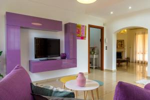 a living room with purple furniture and a tv at Lillà - Home and Garden in Riposto