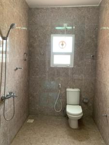 uma casa de banho com um WC, um chuveiro e uma janela. em Al Shraija Castle , Al Jabal Al Akhdar em Al ‘Aqar