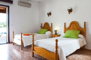 two beds in a bedroom with green pillows at Finca Aguilas in S'Horta