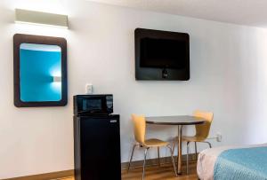Habitación con mesa pequeña y TV en la pared. en Motel-6 Lagrange Ga, en La Grange
