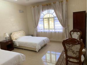 une chambre avec deux lits et une fenêtre et une chaise dans l'établissement Al Shraija Castle , Al Jabal Al Akhdar, à Al ‘Aqar