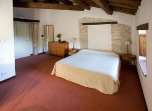 a bedroom with a white bed and a brick wall at Dimora della Fonte in Greccio