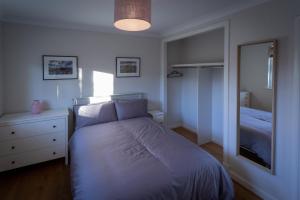 Dormitorio pequeño con cama y espejo en The Salmon Hut, en Aberlour