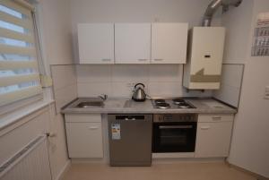 una pequeña cocina con armarios blancos y tetera en AB Apartment Bad-Cannstatt, en Stuttgart