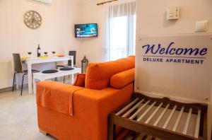 a living room with an orange couch and a table at Konstantina & Evgenia Deluxe Apartment in Nea Peramos