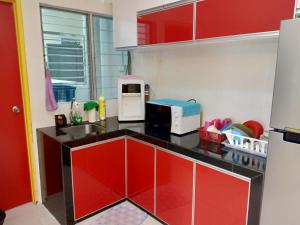 eine Küche mit roten Schränken, einer Spüle und einer Mikrowelle in der Unterkunft WindMill SunRise PaddyView Homestay in Sekinchan