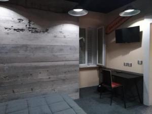 a room with a wooden wall with a desk and a television at Thematic Rooms - AThema Atmosphere in Trieste