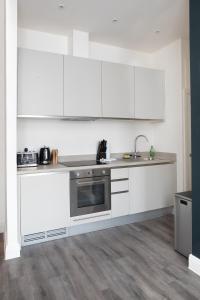 a kitchen with white cabinets and a stainless steel oven at The Portland - City Centre in Bristol