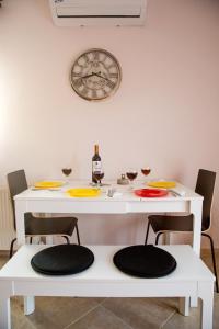 a white table with chairs and a clock on the wall at Konstantina & Evgenia Deluxe Apartment in Nea Peramos