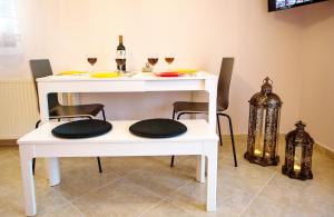 a white table with two chairs and glasses of wine at Konstantina & Evgenia Deluxe Apartment in Nea Peramos