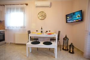 a white table and chairs with a tv on the wall at Konstantina & Evgenia Deluxe Apartment in Nea Peramos