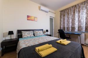 a bedroom with a bed with two yellow towels on it at Alexander Apartments Airport in Spáta