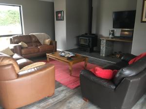 a living room with leather furniture and a fireplace at Sandy Acre in North Loburn