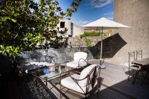 eine Terrasse mit Stühlen, einem Tisch und einem Sonnenschirm in der Unterkunft Gîte de l'Autre Jardin in Mirepoix