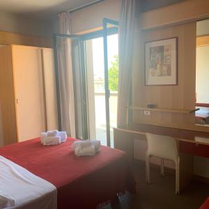 Pokój hotelowy z łóżkiem, biurkiem i oknem w obiekcie Hotel Giglio w Rimini