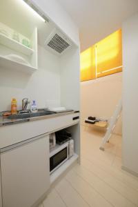 eine weiße Küche mit einer Spüle und einer Mikrowelle in der Unterkunft Nano Kita Shinjuku / Vacation STAY 62654 in Tokio
