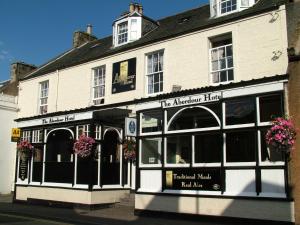 a large white building with flowers in front of it at Aberdour Hotel, Stables Rooms & Beer Garden in Aberdour