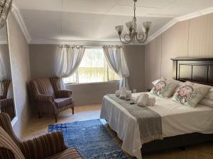 a bedroom with a bed and a chair and a window at Dei Gratia in Pretoria