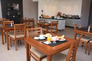 a restaurant with wooden tables and chairs with drinks on them at ID Hotel in Passo Fundo