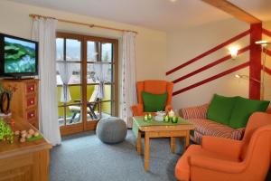a living room with orange chairs and a tv at Landhaus Marie-Theres in Oberstdorf