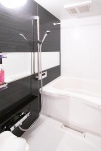 a bathroom with a shower and a white bath tub at Apartment Hotel Tenjin TUMUGU / Vacation STAY 62178 in Susakiuramachi
