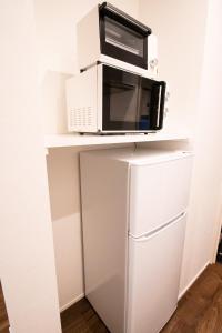 a microwave on a shelf above a refrigerator at Apartment Hotel Tenjin TUMUGU / Vacation STAY 62178 in Susakiuramachi +34 photos
