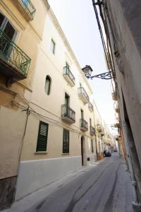 una calle vacía al lado de un edificio con persianas verdes en Mansarda con terrazzo en Trapani