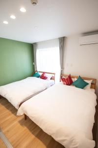 two beds in a room with green and white at Apartment Hotel Tenjin TUMUGU / Vacation STAY 62181 in Susakiuramachi