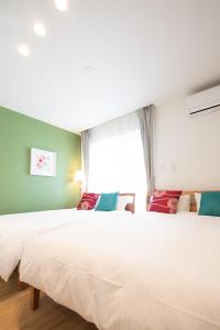 two beds in a room with a window at Apartment Hotel Tenjin TUMUGU / Vacation STAY 62181 in Susakiuramachi