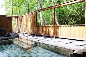 a swimming pool with a wooden fence and a patio at Case House Hokkaido / Vacation STAY 61607 in Higashikawa