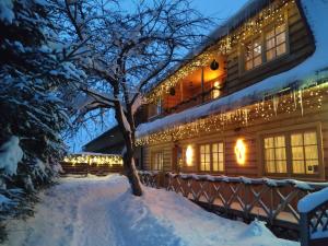 un edificio cubierto de luces de Navidad en la nieve en Agroturystyka Sarenka, en Podsarnie