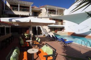 a patio with tables and chairs next to a swimming pool at Vicky Apartments in Nikiana