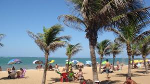 Leute an einem Strand mit Palmen und dem Meer in der Unterkunft Apto Praia de Itapoã 2 qto c/ar in Vila Velha