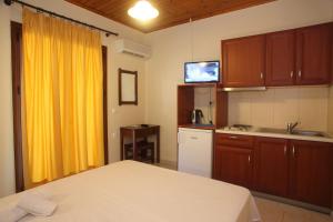 a kitchen with a bed and a yellow curtain at Vicky Apartments in Nikiana