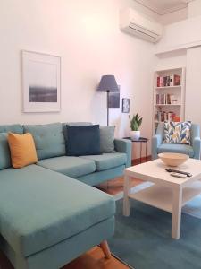 een woonkamer met een blauwe bank en een tafel bij Colourful Apartment in the heart of Athens in Athene