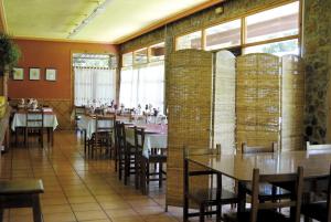 a dining room with tables and chairs and windows at Camping Berceo in Berceo