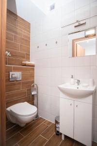 a white bathroom with a toilet and a sink at Apartamenty GoszoWita in Stronie Śląskie