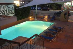 a large swimming pool with chairs and an umbrella at Vicky Apartments in Nikiana