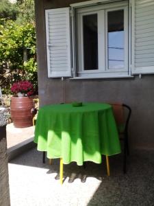 a table with a green table cloth sitting under a window at Apartments Laura in Stara Baška