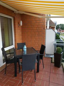 d'une terrasse avec une table, des chaises et un mur en briques. dans l'établissement Ferienwohnung Sonnenschein mit großem Balkon, à Grömitz