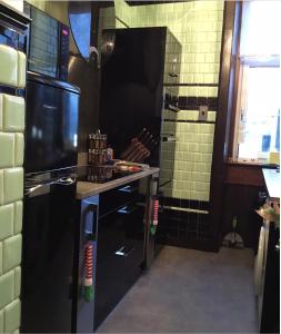 ポート・グラスゴーにあるVictorian flatのキッチン(黒い冷蔵庫、カウンター付)
