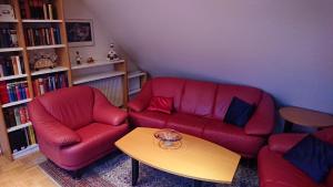 ein Wohnzimmer mit einem roten Sofa und einem Tisch in der Unterkunft Ferienwohnung Dachspitze mit Tiefgaragenstellplatz und Skiraum in Kurort Oberwiesenthal