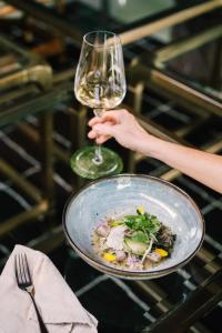 uma pessoa segurando um copo de vinho e uma tigela de comida em Casa 41 em Escazú