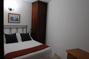 フロンテーラにあるApartamentos Edalmarのベッドルーム1室(ベッド1台付)、木製キャビネットが備わります。